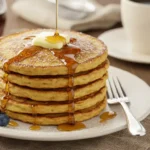 A delicious stack of fluffy French toast pancakes topped with butter and maple syrup