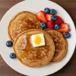 Buckwheat Pancakes on a Plate Topped with Syrup and Berries