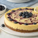Whole lemon blueberry cheesecake topped with blueberry sauce and lemon slices