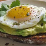 Plate of avocado toast with poached egg and herbs