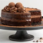 Full chocolate truffle cake on a stand topped with ganache and truffles