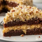 Slice of German chocolate poke cake with coconut pecan frosting