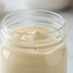 Glass bottle of creamy homemade coffee creamer on wooden counter