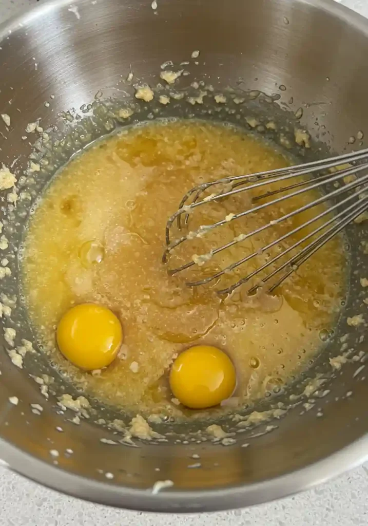 Bowl of eggs, sugar, oil, and vanilla being whisked