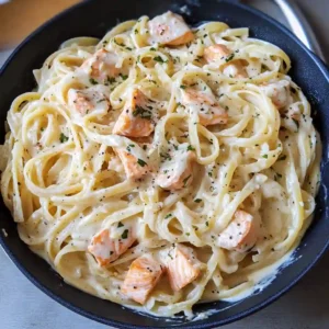 A bowl of salmon Alfredo pasta garnished with parsley
