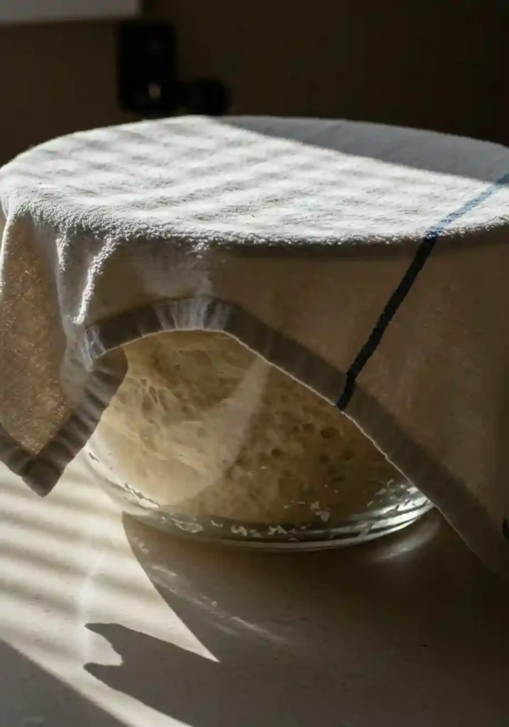 Gluten free pizza dough resting in a covered bowl