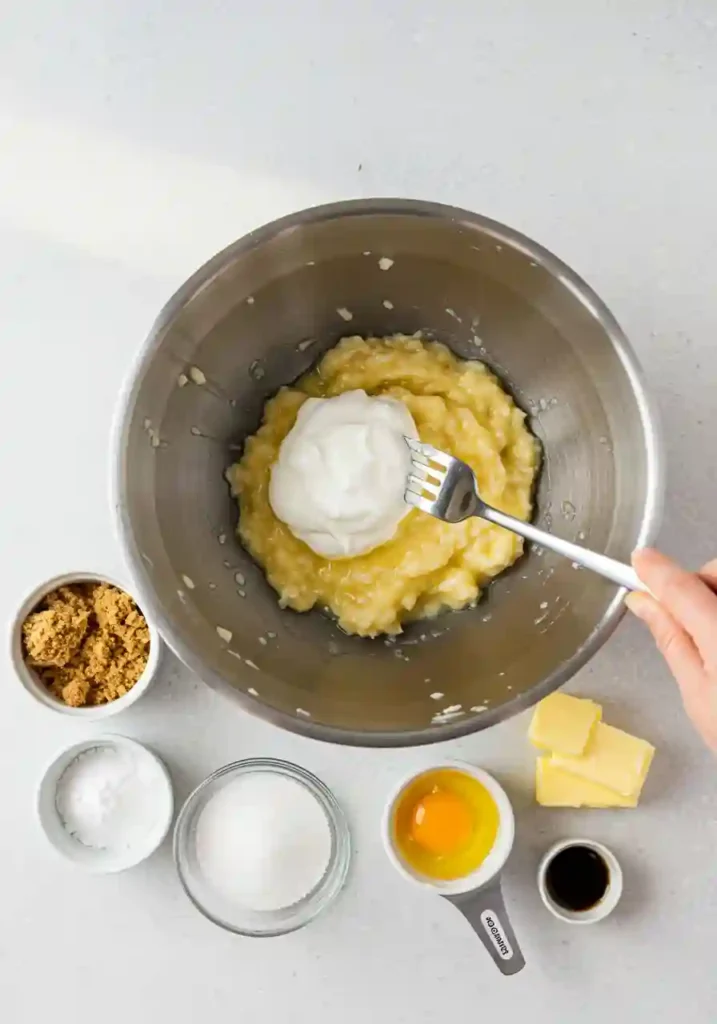 Wet ingredients like bananas, yogurt, and eggs mixed in a bowl