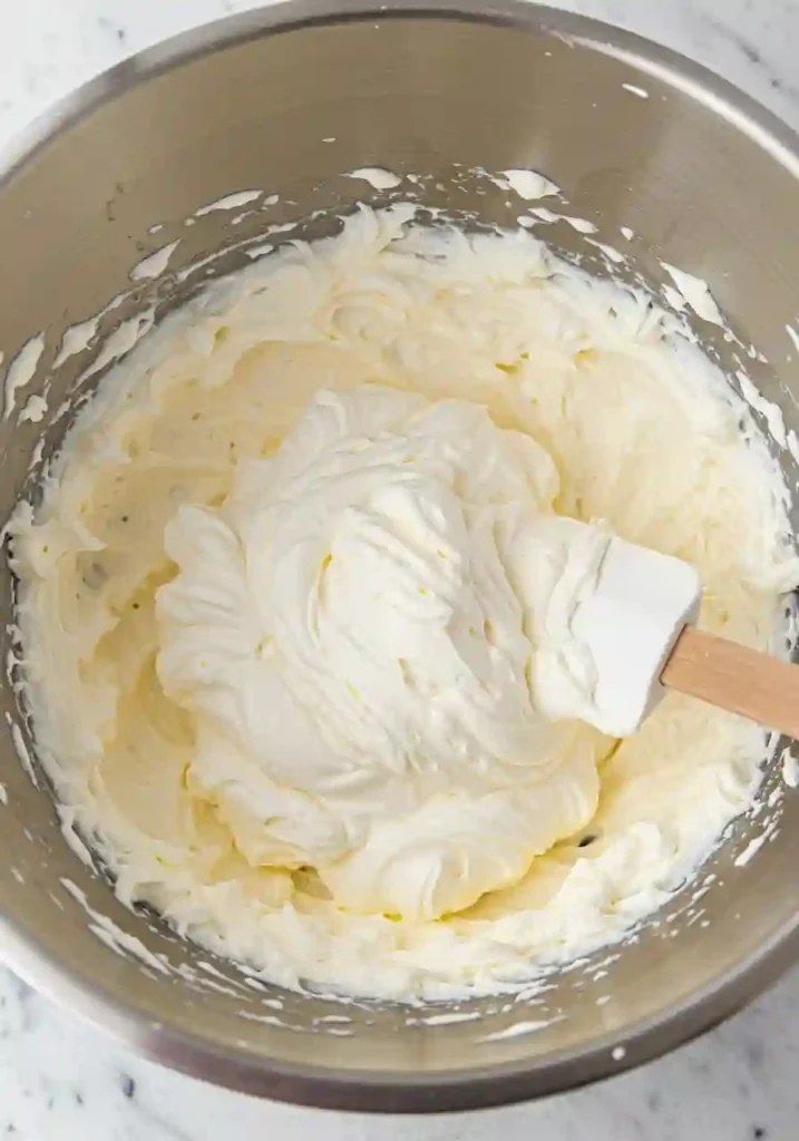 Beating cream cheese and sugar in a bowl for cheesecake filling