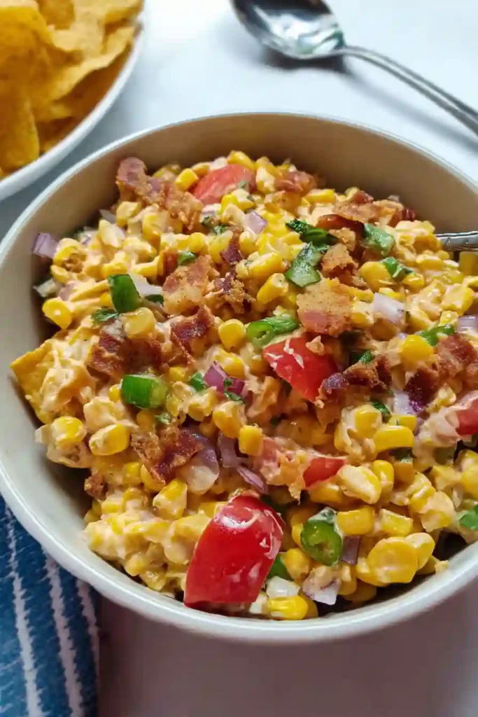 Crushed Fritos being folded into creamy corn salad just before serving