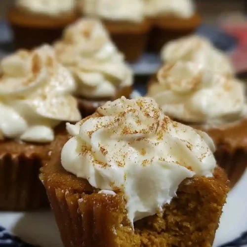 Piping creamy pumpkin pie filling into center of baked cupcakes using pastry bag