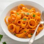 Colorful raw carrot salad with fresh herbs in white bowl on wooden table