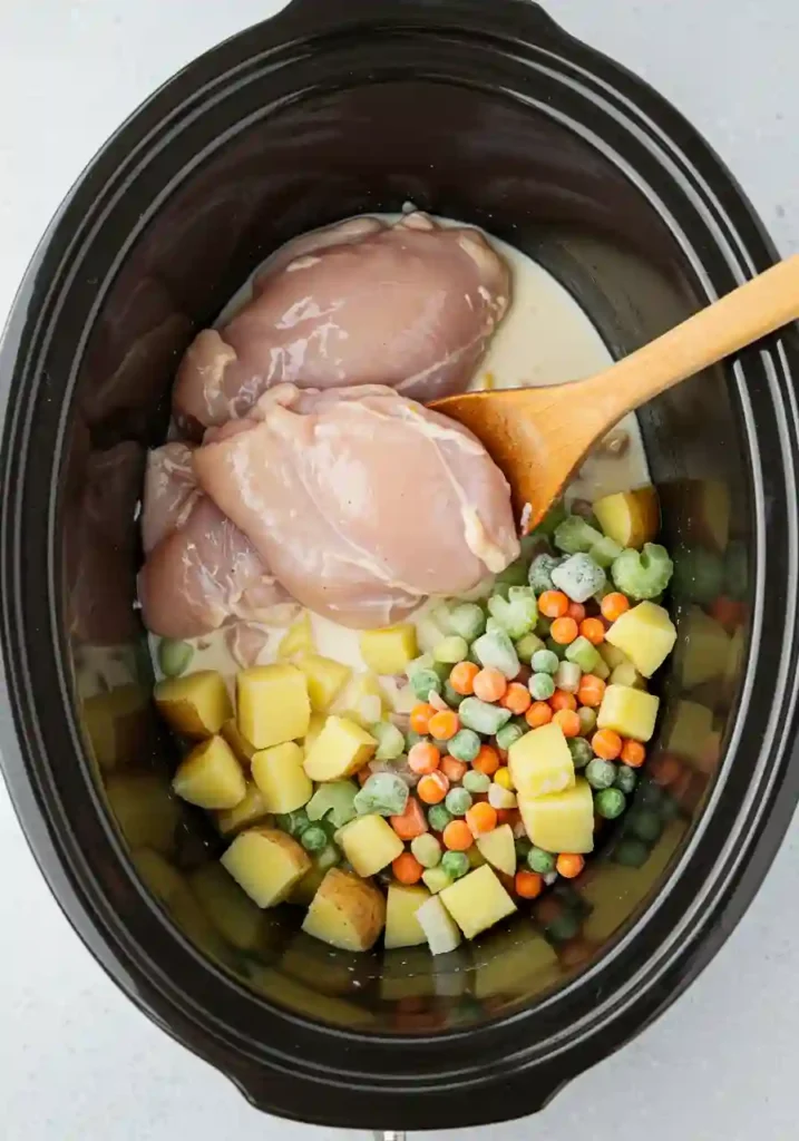 Ingredients layered in a crock pot before cooking chicken pot pie