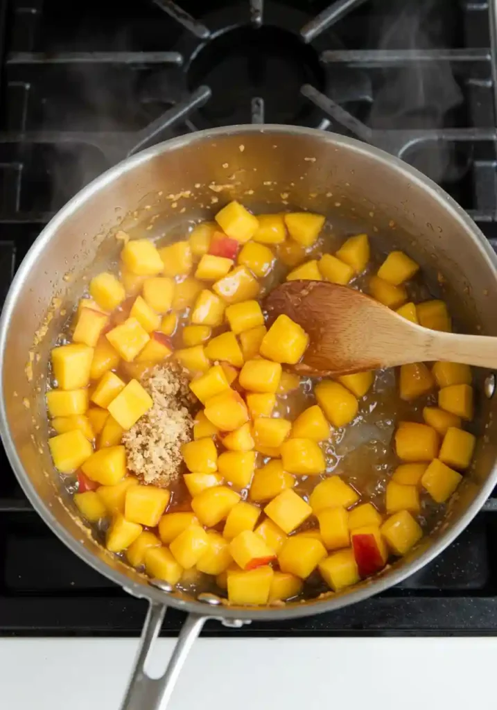 Diced peaches cooking in saucepan with sugar and spices for peach cobbler cookie filling
