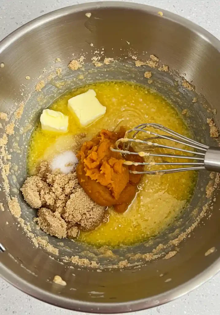 Hands whisking together flour, spices, baking soda and salt in large glass mixing bowl for pumpkin white chocolate chip cookies