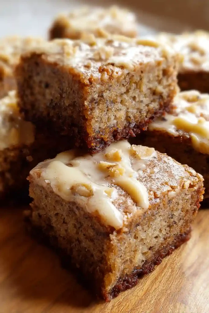 Spreading glossy brown butter frosting on cooled banana brownies with offset spatula in baking pan