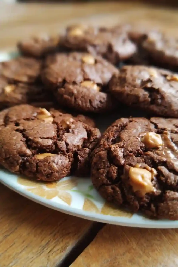 Chocolate peanut butter cookies baking on parchment-lined sheet in oven with slightly soft centers