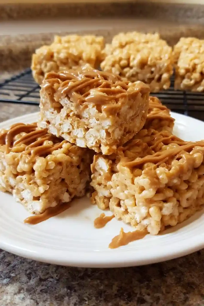 Hands pressing peanut butter rice krispie mixture evenly into a parchment-lined baking pan with a spatula
