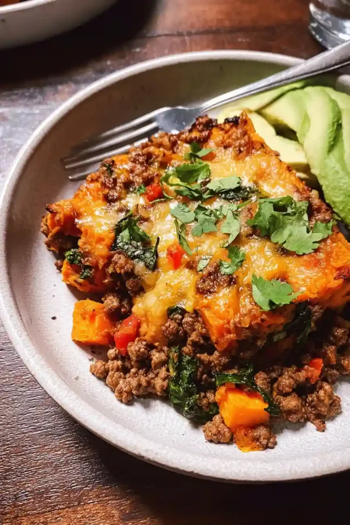 Finished sweet potato and ground beef skillet being garnished with cilantro and lime